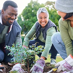 Group of volunteers smiling while planting a tree