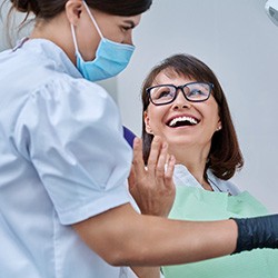 Woman smiling with dentist while reviewing X-ray