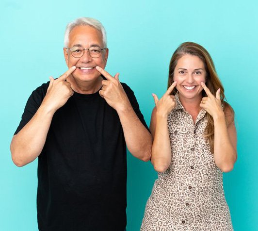 Happy mature couple pointing at their teeth