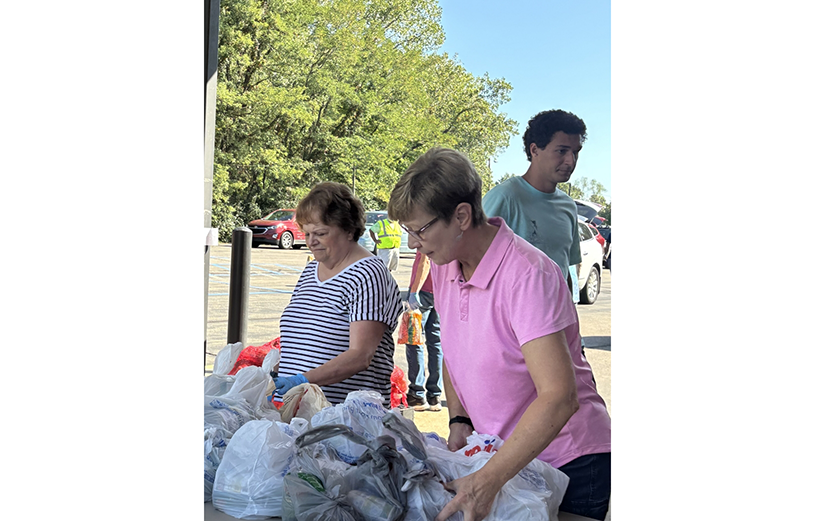 Two women picking up trash bags