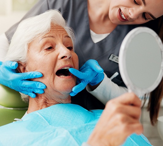 Woman looking in the mirror at her dentures in Stevensville