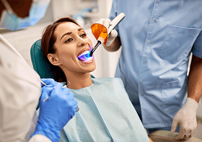 Dentist applying UV light to patient’s dental filling.