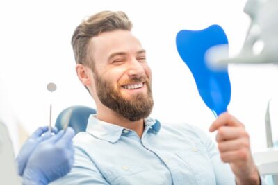 A smiling man seated in a dental chair.